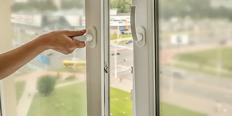 Fenetre_ouverture_oscillo_et_battant Femme réduisant les nuisances sonores en fermant une fenêtre