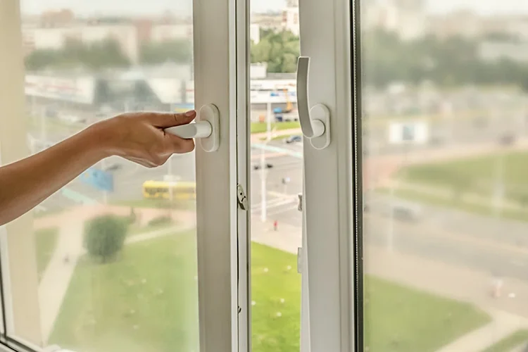 Femme réduisant les nuisances sonores en fermant une fenêtre